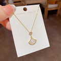 Gold-tone necklace with a white fan-shaped pendant displayed on a jewelry card.