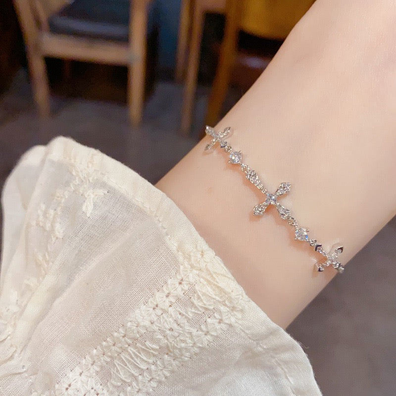 Silver-tone triple cross slider bracelet worn on a wrist.