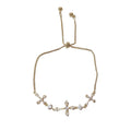 Gold-tone triple cross bracelet with an adjustable slider clasp on a white background.